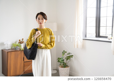 Woman standing indoors with a shoulder bag Woman standing indoors with a shoulder bag 120856470