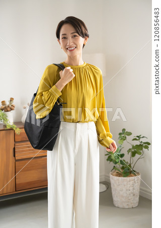 Woman standing indoors with a shoulder bag Woman standing indoors with a shoulder bag 120856483