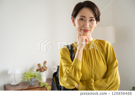 Woman standing indoors with a shoulder bag 120856488