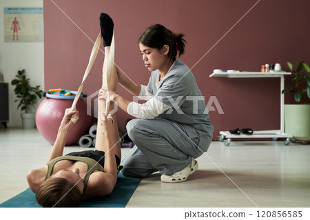 Physical Therapist Assisting Woman with Stretching Exercise Physical Therapist Assisting Woman with Stretching Exercise 120856585