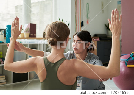 Practicing Yoga with Instructor in Modern Studio Setting 120856593