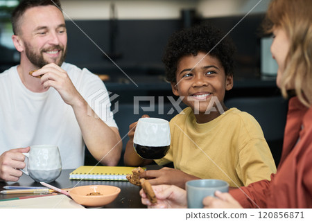 Smiling Child Enjoying Breakfast with Family Members Smiling Child Enjoying Breakfast with Family Members 120856871