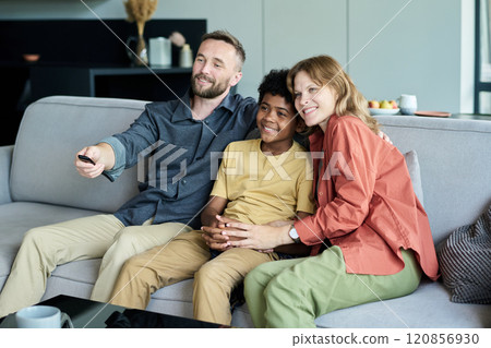 Smiling Family Sitting on Sofa and Watching TV Together Smiling Family Sitting on Sofa and Watching TV Together 120856930