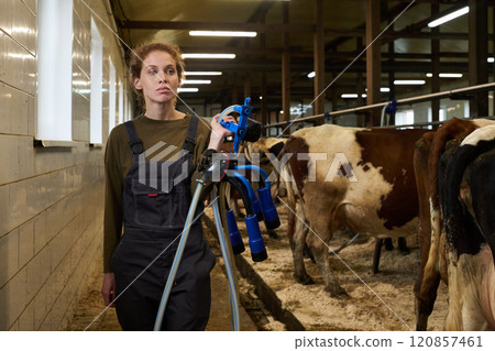 Female farmer carrying milking machine Female farmer carrying milking machine 120857461