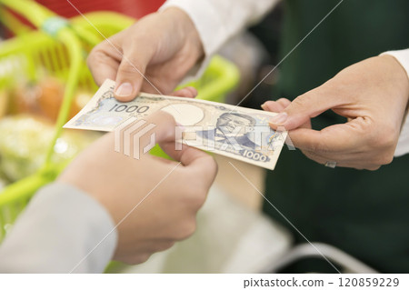 年輕女子在超市收銀台交出新帳單 年輕女子在超市收銀台交出新帳單 120859229