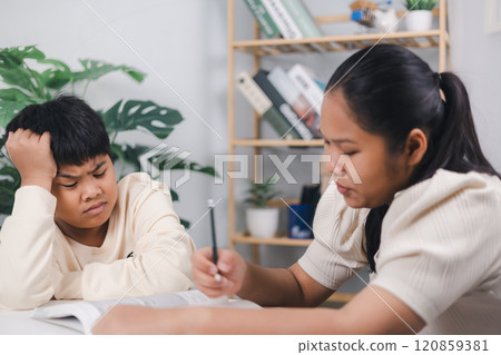 Female tutor helping little elementary school boy with homework during individual lesson at home, Sister helping boy writing lesson and learning to write, Education home school concept. Female tutor helping little elementary school boy with homework during individual lesson at home, Sister helping boy writing lesson and learning to write, Education home school concept. 120859381