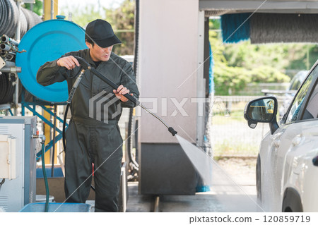 身穿連身褲的男性機械師使用高壓清洗機的洗車槍洗車 120859719