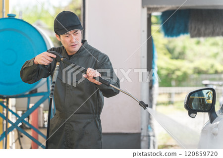 身穿連身褲的男性機械師使用高壓清洗機的洗車槍洗車 120859720
