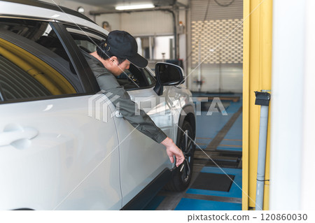 一名男性汽車修理工在汽車修理廠修理車輛 一名男性汽車修理工在汽車修理廠修理車輛 120860030