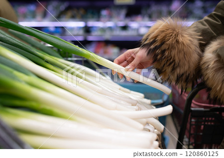 Woman's hands choosing green onions 120860125
