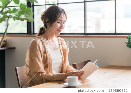 Woman reading while drinking coffee at a cafe 120860811