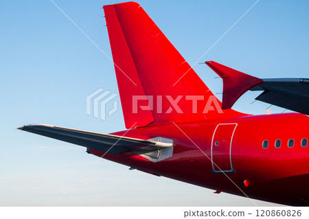 Tail and rear of the passenger airplane of red color against the blue sky Tail and rear of the passenger airplane of red color against the blue sky 120860826