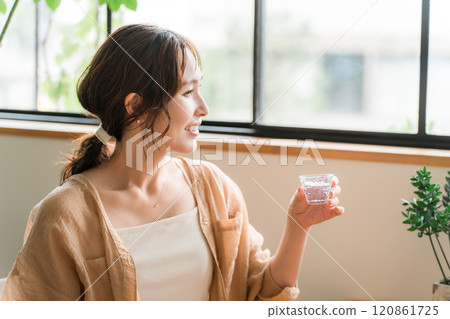 Young Asian woman drinking sake from a chilled glass Young Asian woman drinking sake from a chilled glass 120861725