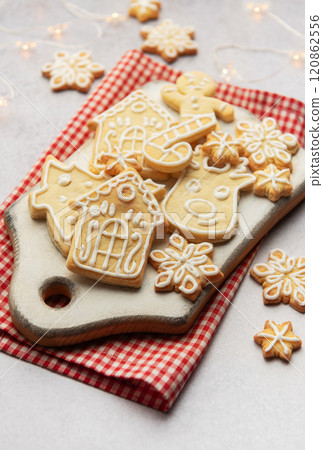 Christmas cookies decorated with icing lying on white cutting board Christmas cookies decorated with icing lying on white cutting board 120862556