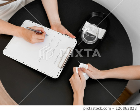 Therapy session with counselor taking notes and client holding tissues Therapy session with counselor taking notes and client holding tissues 120862828