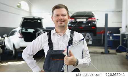 Qualified maintenance centre worker in special uniform posing on cars background 120862941