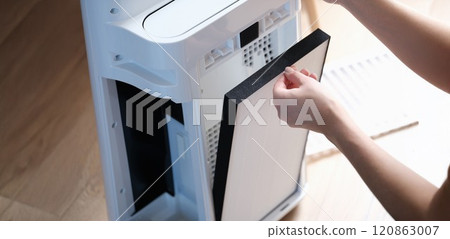 A woman removes the filter from the air ionizer A woman removes the filter from the air ionizer 120863007