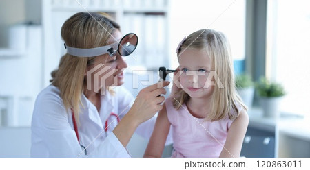 A woman otolaryngologist in a clinic looks at the ear of a girl 120863011