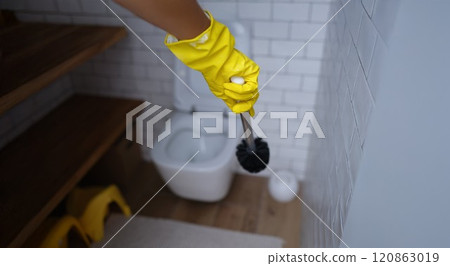 A hand in a rubber glove with a toilet brush in the toilet A hand in a rubber glove with a toilet brush in the toilet 120863019