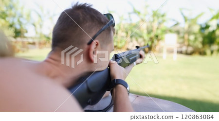 A man is aiming at a target with a gun, close-up 120863084