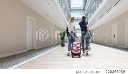 Couple walking with luggage along the hotel corridor Couple walking with luggage along the hotel corridor 120863089