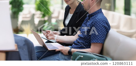 A man with a laptop and a woman with a tablet are talking 120863111