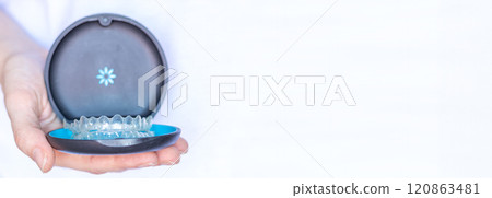 Banner hand holding Invisalign transparent braces on white background with copy space. Orthodontic invisible retainers and aligners Banner hand holding Invisalign transparent braces on white background with copy space. Orthodontic invisible retainers and aligners 120863481