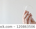 Hand holding Invisalign transparent braces on white background with copy space. Orthodontic invisible retainers and aligners 120863506