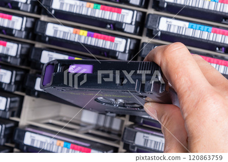 hand of a technician holding data storage magnetic tape in front 120863759