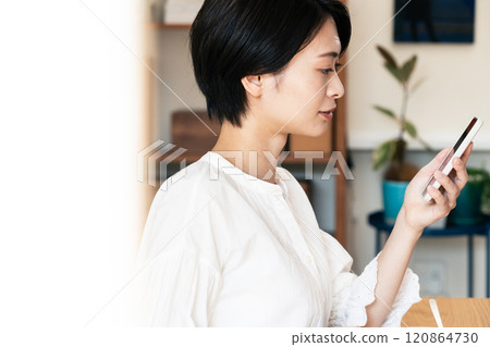 一個女人一邊吃飯一邊看一部智能手機 120864730