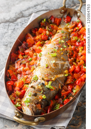 Whole sea bass stewed with bell pepper, onion, tomatoes, garlic and celery close-up in a frying pan. Vertical Whole sea bass stewed with bell pepper, onion, tomatoes, garlic and celery close-up in a frying pan. Vertical 120864763