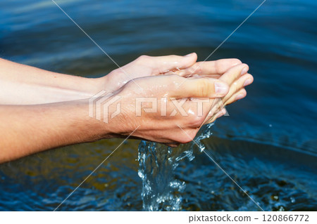 Person scooping raw water from lake to promote environmental awareness in natural resource conservation 120866772
