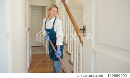 woman wearing blue apron and headscarf mopping floor in well-lit hallway, cleaning service, professional housekeeper, domestic chores, home maintenance, residential cleaning 120866903