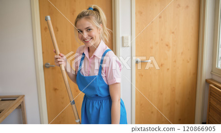 Woman in blue apron mopping floor in bright hallway, cleaning service concept, professional housekeeper, home maintenance, residential cleaning, clean environment, housekeeping duties, indoor cleaning 120866905