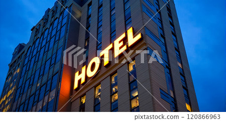 Modern hotel building exterior at dusk, illuminated signage, urban accommodation, high-rise architecture, city travel lodging destination, evening lights, hospitality industry structure Modern hotel building exterior at dusk, illuminated signage, urban accommodation, high-rise architecture, city travel lodging destination, evening lights, hospitality industry structure 120866963