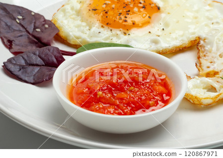 Fried egg and red sauce on the plate. Fried egg and red sauce on the plate. 120867971
