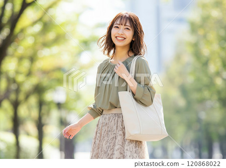 A young businesswoman smiling while going to work amidst the fresh greenery 120868022
