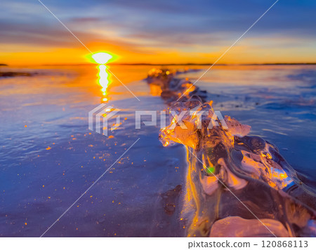 Frosty air and frozen lake surface in a beautiful sunset landscape. Beautiful ice shapes and sunlight. Photo from Sotkamo, Finland. 120868113