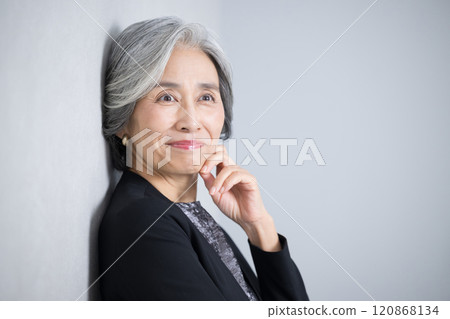 畫面中，一位白髮蒼蒼、穿著西裝、手托著下巴思考的公司女總裁，神情苦惱又煩惱。 120868134