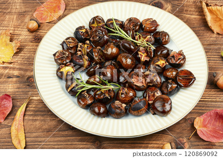 Cracked roasted chestnuts on rustic wooden table. 120869092