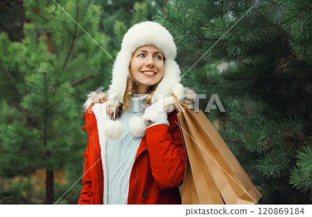 Happy smiling young woman with shopping bag in winter against Christmas tree, holiday shopping Happy smiling young woman with shopping bag in winter against Christmas tree, holiday shopping 120869184