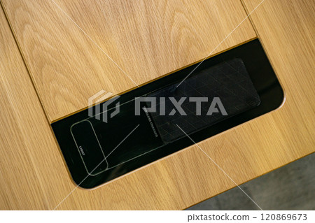 Mobile phone with wireless charger on table. Modern workplace accessory 120869673