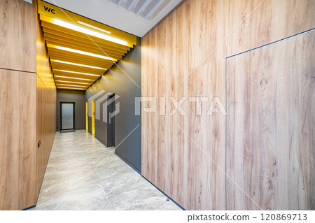 Perspective of a long corridor in office building. Doors of washrooms in hallway. Doors in office with wc signs. Entrance to restrooms in a factory Perspective of a long corridor in office building. Doors of washrooms in hallway. Doors in office with wc signs. Entrance to restrooms in a factory 120869713