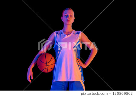 Portrait of confident teen girl, basketball player proudly standing and posing with ball against black studio background in neon light Portrait of confident teen girl, basketball player proudly standing and posing with ball against black studio background in neon light 120869862