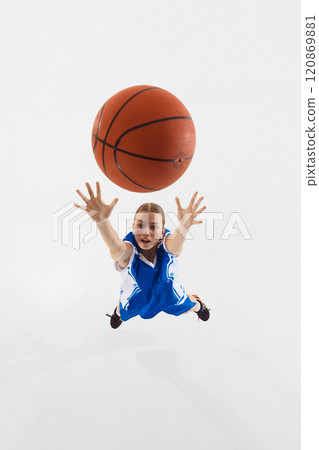 Motivated teen girl in blue uniform, basketball player throwing ball into basket, training against white studio background. Top view Motivated teen girl in blue uniform, basketball player throwing ball into basket, training against white studio background. Top view 120869881