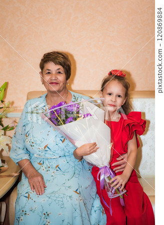 Russian granddaughter holding bouquet from her grandmother for birthday 120869884