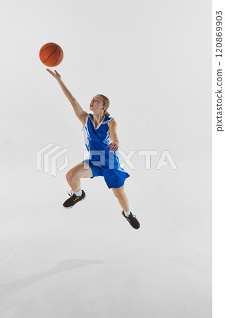 Scoring a goal. Full-length dynamic image of young teen girl in blue uniform in motion, training, playing against white studio background 120869903