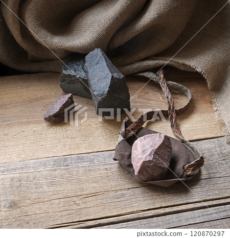An antique leather sling lies on wooden desk 120870297