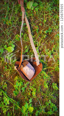 An antique leather sling lies on the ground 120870305