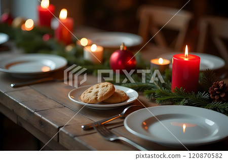 The warm and inviting holiday table features decorated pine branches and flickering red candles, creating a charming atmosphere The warm and inviting holiday table features decorated pine branches and flickering red candles, creating a charming atmosphere 120870582